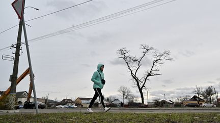 A woman walks alone on a street in the outer suburbs of Kyiv, February 2024.  (Sergei Supinsky/AFP)