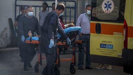 Medical personnel carry a survivor on a stretcher outside a warehouse in the port city of Kalamata on June 15, 2023, after a boat carrying dozens of migrants sank in international sea waters Ionian.  (ANGELOS TZORTZINIS / AFP)