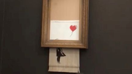 Une œuvre du street artiste Banksy s'auto-détruit en pleine vente aux enchères, chez Sotheby's, le 5 octobre 2018 à Londres. (INSTAGRAM / @PIERREKOUKJIAN / INSTAGRAM / @SINCEFINEART / REUTERS)