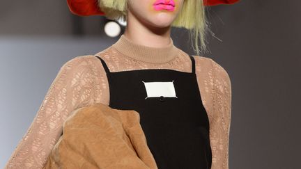 Le show s'est tenu dans une salle toute blanche reprenant une couleur fétiche de la Maison Margiela. Sur un podium au sol réfléchissant ont défilé des silhouettes à l'excentricité chère au couturier britannique de 54 ans : chevelures couleur anis ou poil de carotte, chaussures en fourrure et maquillage multicolore. Dans cette collection qui "célèbre l'innocence", selon le communiqué accompagnant le défilé, "les vêtements interrogent l'idée de conformité". Ici la finesse d'une longue robe noire en dentelle contraste avec des gants rappelant ceux d'une ménagère. Clin d'oeil aux codes de la Maison Margiela, une étiquette blanche se retrouve placée sur le devant d'une robe. Le couturier a aussi exprimé son romantisme avec des silhouettes aux accents rétro, avec des fleurs imprimées sur du velours, des plumes et des chaussures à brides. Galliano s'est abstenu de venir saluer à la fin du défilé, contrairement à ce qu'il avait fait furtivement à Londres lors du défilé couture, en janvier. Une attitude de discrétion conforme à l'esprit de la griffe, dont le fondateur Martin Margiela -qui l'a aujourd'hui quittée-, a toujours cultivé le secret autour de lui.
 (BERTRAND GUAY / AFP)