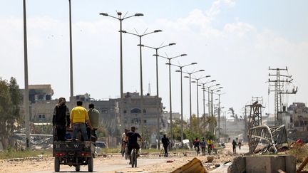 Des Palestiniens circulent sur une route qui passe devant des bâtiments endommagés et détruits à Khan Younes, le 7 avril 2024. (AFP)