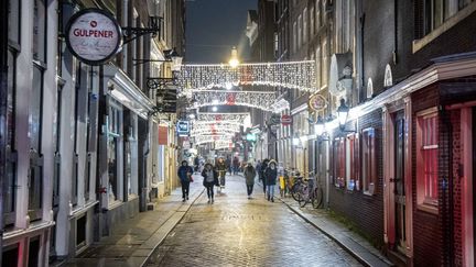 Des passants dans une rue d'Amsterdam, le 19 décembre 2021, premier jour du confinement décidé&nbsp;par les autorités des Pays-Bas et qui doit durer jusqu'au 14 janvier 2022 au moins. (NICOLAS ECONOMOU / NURPHOTO)