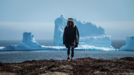 Une résidente de l'île de Terre-Neuve au Canada pose devant l'iceberg, le 16 avril 2017, près de Ferryland. (GREG LOCKE / REUTERS)