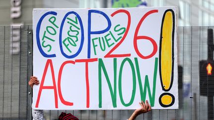 La pancarte d'un manifestant à Glasgow, qui indique : "COP26 : agissez maintenant !", pour l'ouverture en Ecosse de la Conférence des Nations Unies sur le Climat, ce 1er novembre 2021.&nbsp; (HASAN ESEN / ANADOLU AGENCY via AFP)