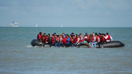 Des migrants sont assis à bord d'un bateau pneumatique avant de tenter de traverser la Manche pour rejoindre la Grande-Bretagne, au large de Sangatte (Pas-de-Calais), le 18 juillet 2023. (BERNARD BARRON / AFP)