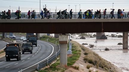 Des véhicules de l'armée sont arrivés en renfort, vendredi, tandis qu'au-dessus d'eux, sur un pont, des volontaires se dirigeaient vers La Torre. (MANAURE QUINTERO / AFP)