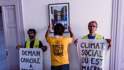 Une opération de décrochage du portrait d'Emmanuel Macron par des militants d'ANV-COP21, dans la mairie de Lingolsheim (Bas-Rhin), le 29 juillet 2019. (CHRISTOPH DE BARRY / HANS LUCAS / AFP)