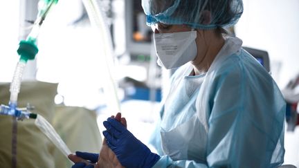 Un membre de l'équipe médicale de l'hôpital Georges-Pompidou (Paris) s'occupe d'un patient touché par le Covid-19, dans le service de réanimation, le 6 avril 2021. (ANNE-CHRISTINE POUJOULAT / AFP)