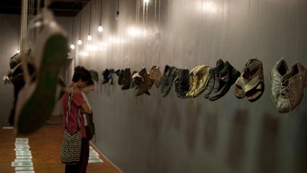 Des visiteurs observent les chaussures suspendues, ainsi que les empreintes de pas légendées sur le sol, au Musée "Maison de la Mémoire indomptée" de Mexico (9 mai 2016)
 (Yuri Cortez / AFP)