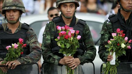 Des soldats tha&iuml;landais posent avec des roses offertes par la population &agrave; Bangkok (Tha&iuml;lande), le 27 mai 2014. (WASON WANICHAKOM / AP / SIPA)