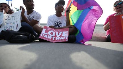 "L'amour ne peut attendre", proclame cette pancarte d'un militant pro-mariage gay, qui tient &eacute;galement un drapeau arc-en-ciel pr&egrave;s de la Cour supr&ecirc;me, &agrave; Washington,&nbsp;qui a d&eacute;cid&eacute; vendredi 26 juin la l&eacute;galit&eacute; du mariage des couples de m&ecirc;me sexe dans les 50 Etats am&eacute;ricains. (ALEX WONG / GETTY IMAGES NORTH AMERICA/AFP)