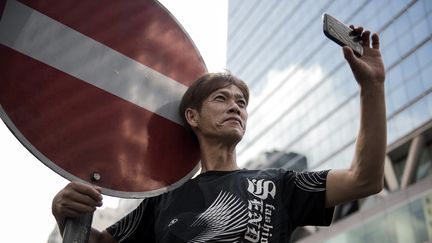 Un homme prend une photo avec son t&eacute;l&eacute;phone dans le district de Kowloon, &agrave; Hong Kong, le 29 septembre 2014. (ALEX OGLE / AFP)