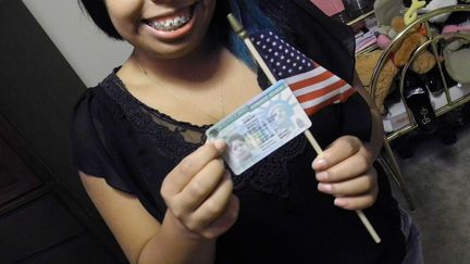 Une jeune immigr&eacute;e pose avec sa "green card", le 31 juillet &agrave; Cumming (G&eacute;orgie,&nbsp;Etats-Unis).&nbsp; (ASHLEY HOPKINSON / AP / SIPA)