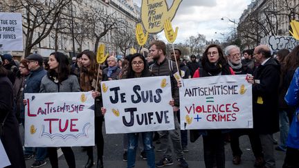 Des manifestants portent des pancartes dénonçant l'antisémitisme, le 28 mars 2018, à Paris, pendant une marche blanche en hommage à Mireille Knoll, octogénaire juive tuée dans la capitale. (BENJAMIN FILARSKI / HANS LUCAS / AFP)