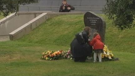 Une femme et sa fille d&eacute;posent un bouquet de fleurs sur la st&egrave;le d&eacute;di&eacute;e aux victimes de l'attentat de Karachi, &agrave; Cherbourg (Manche), le 8 mai 2012. (FTVI / FRANCE 3)