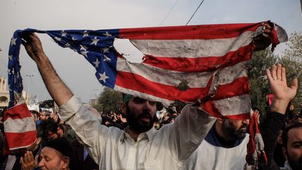 Un manifestant brandit le drapeau américain brûlé lors d'une manifestation anti-américaine à Téhéran le 3 janvier 2020. (ROUZBEH FOULADI / MAXPPP)