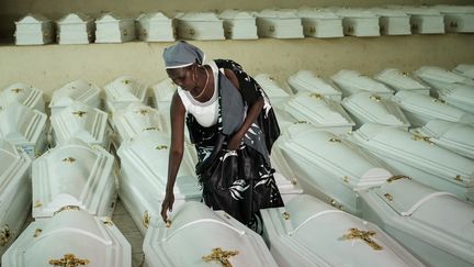 Une survivante du génocide de 1994 au Rwanda se penche sur l'un des cercueils&nbsp;des victimes, le 2 mai 2019, à l'occasion de funérailles au mémorial de Kigali. (YASUYOSHI CHIBA / AFP)