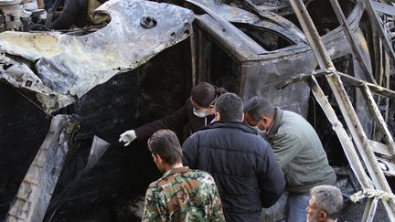 Les autorités syriennes inspectent la carcasse d'une voiture après un attentat suicide, à Damas, dimanche 31 janvier 2016.&nbsp; (LOUAI BESHARA / AFP)