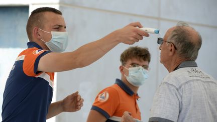 Un sauveteur de la protection civile prend la température d'un homme avant de subir un test COVID-19, à Laval, dans l'ouest de la France, le 17 juillet 2020. (JEAN-FRANCOIS MONIER / AFP)