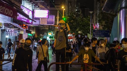 Un manifestant avec un masque à gaz pointe un laser, signe de protestation contre les violences policières, devant le commissariat de Shum Shui Po, à Hong Kong (Chine), le 14 août 2019.&nbsp; (VERNON YUEN / NURPHOTO / AFP)