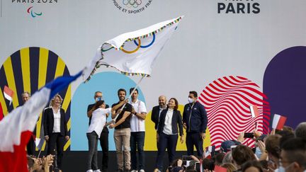 La maire de Paris Anne Hidalgo, le présidente du COJO Paris 2024 Tony Estanguet, la ministre des Sports Roxana Maracineanu, et la présidente du CNO France Brigitte Henriques avec le drapeau olympique des Jeux Olympiques, le 9 août 2021, à Paris. (AGENCE KMSP / AFP)