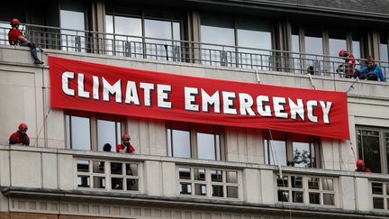 Des militants écologistes déploient une banderole à l'extérieur du siège de la compagnie British Petroleum, lundi 20 mai 2019 à Londres (Royaume-Uni). (ADRIAN DENNIS / AFP)