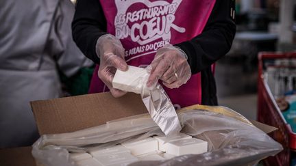 Des bénévoles des Restos du Cœur mettent dans des paquets destinés aux bénéficiaires des savons recyclés fabriqués à partir des savons usagés des hôtels, le 24 mars 2021 à Givors (Rhône). (JEFF PACHOUD / AFP)