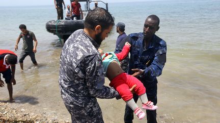 Des gardes-côtes libyens portent le corps d'un bébé mort dans le naufrage d'un bateau au large de la Libye, le 29 juin 2018. (MAHMUD TURKIA / AFP)