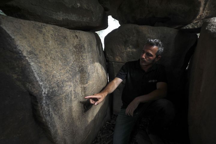 Uri Berger étudie les dessins gravés sur ces dolmens, vieux d'environ 4000 ans. (MENAHEM KAHANA / AFP)