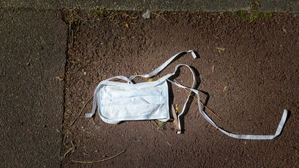 Un&nbsp;masque de protection usager jeté sur un trottoir, à Roncq (Nord), le 10 avril 2020. Photo d'illustration. (THIERRY THOREL / MAXPPP)