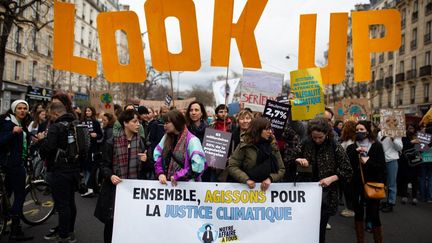 Des manifestants avec des une banderole "Ensemble agissons pour la justice climatique", de l'ONG Notre Affaire à tous, le 12 mars 2022 à Paris. (RAPHAEL KESSLER / HANS LUCAS / AFP)