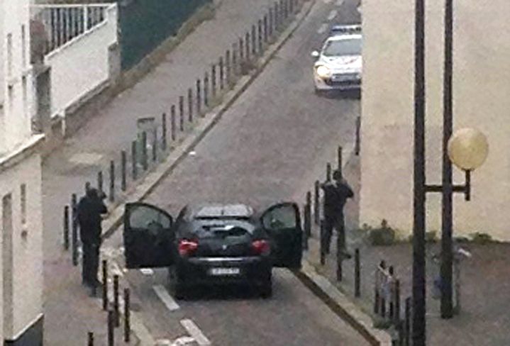 Deux hommes arm&eacute;s montent &agrave; bord d'un v&eacute;hicule apr&egrave;s l'attaque men&eacute;e dans les locaux de "Charlie Hebdo", &agrave; Paris, le 7 janvier 2015. (ANNE GELBARD / AFP)