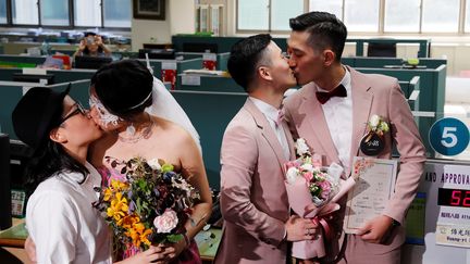 Deux couples taïwanais s'embrassent après avoir fait enregistrer leur mariage civil à Taipei, capitale de Taïwan, le 24 mai 2019, jour d'entrée en vigueur de l'autorisation du mariage homosexuel dans le pays. (TYRONE SIU / REUTERS)