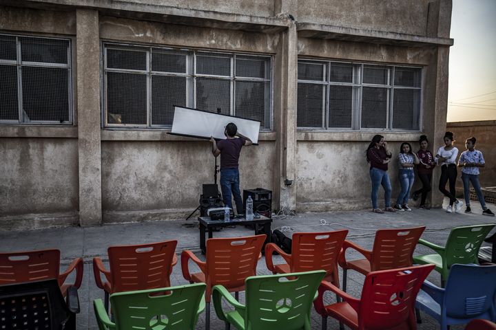 Un membre du cinéma itinérant du réalisateur Shero Hinde installe un écran de cinéma.&nbsp; (DELIL SOULEIMAN / AFP)