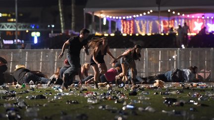 Des gens s'enfuient et tentent de se protéger, lors de la fusillade survenue à Las Vegas, le 1er octobre 2017. (DAVID BECKER / GETTY IMAGES NORTH AMERICA / AFP)