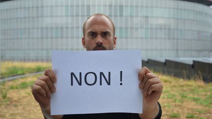 Un homme porte une feuille où est écrit "non !" (JEAN-CHRISTOPHE BOURDILLAT / RADIO FRANCE)