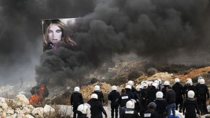 Des policiers palestiniens se tiennent pr&egrave;s de pneus en feu allum&eacute;s pr&egrave;s du camp de r&eacute;fugi&eacute;s de Jalazone aux abords de Ramallah (Palestine), le 12 janvier 2014. (MOHAMAD TOROKMAN / REUTERS)