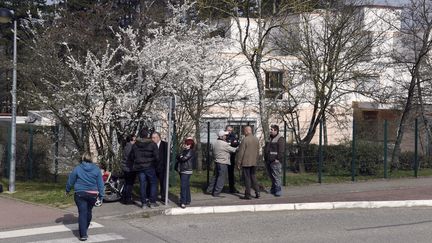 Des parents et des enqu&ecirc;teurs devant&nbsp;l'&eacute;cole de Mas de la Ras, &agrave; Villefontaine (Is&egrave;re), le 24 mars 2015. (PHILIPPE DESMAZES / AFP)