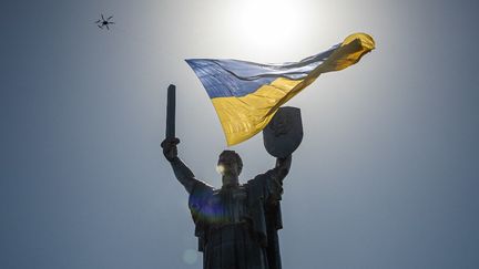 Un drone volant avec un drapeau national ukrainien géant, passe au-dessus du monument de la Patrie lors de la fête de l'indépendance de l'Ukraine, le 24 août 2022. (DIMITAR DILKOFF / AFP)