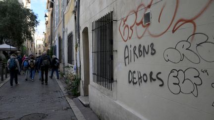 Un graffiti sur un mur, le 10 novembre 2023, proteste contre la présence de locations "Airbnb" dans le quartier du Panier, une zone touristique de Marseille. (NICOLAS TUCAT / AFP)