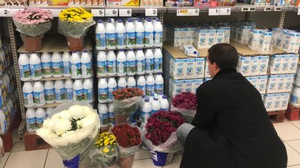 Un producteur de lait dépose des chrysanthèmes devant des produits laitiers dans un supermarché de&nbsp;Clermont-Ferrand. (CLAUDIE HAMON / FRANCE-BLEU PAYS D’AUVERGNE)