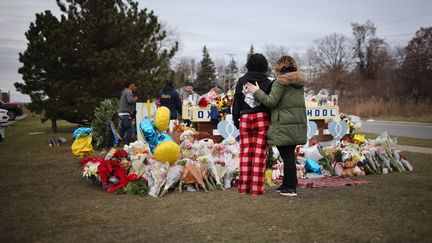 Des passants se recueillent devant le mémorial installé devant le lycée d'Oxford (Etats-Unis), le 3 décembre 2021. (SCOTT OLSON / GETTY IMAGES NORTH AMERICA / AFP)