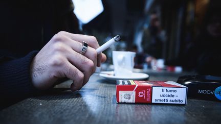 Une personne fume une cigarette à la table d'un bar. (SALESSE FLORIAN / MAXPPP)