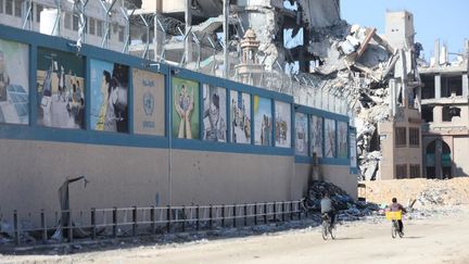 Des personnes en vélo devant le quartier général de l'UNRWA à Gaza, détruit par des frappes israéliennes, le 21 février 2024. (DAWOUD ABO ALKAS / ANADOLU / AFP)