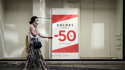 Une femme passe devant un magasin avec une enseigne de soldes à Bordeaux, le 18 juillet 2020. (PHILIPPE LOPEZ / AFP)