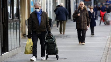 Un homme portant un masque de protection et des gants, faisant ses courses à Paris le 13 mars 2020. (MEHDI TAAMALLAH / NURPHOTO)