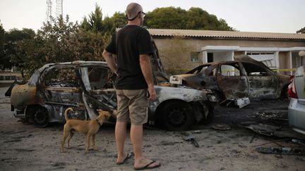  (Un homme regarde une voiture carbonisée dans un kibboutz, à la frontière de Gaza, le 25 août dernier © Tsafrir Abayov/AP/SIPA)