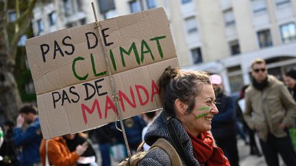 Une manifestante tient une pancarte "Pas de climat, pas de mandat" lors d'une marche pour le climat à Rennes le 12 mars 2022. (DAMIEN MEYER / AFP)