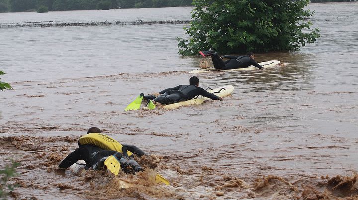 Des secouristes se servent de leur planche de surf pour aller chercher des personnes victimes des inondations &agrave; Cambo-les-Bains (Pyr&eacute;n&eacute;es-Atlantiques), le 4 juillet 2014. (DANIEL VELEZ / AFP)