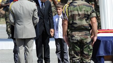 Sarkozy tenant la main d'un des fils du capitaine Mezzasalma, lors de la cérémoine, à Fréjus, le 27/08/10 (AFP/Gérard Julien)